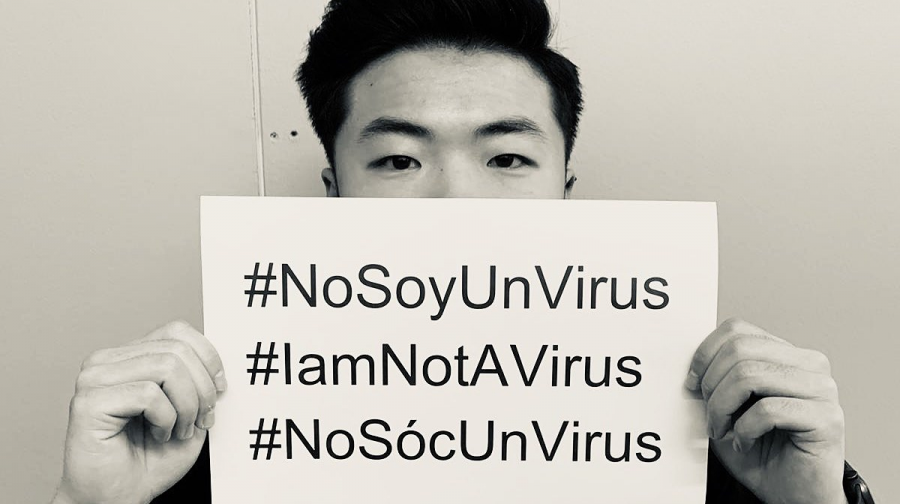 Jia Liang Sun-Wang, based in Spain, holds a sign in response to coronavirus-based discrimination.