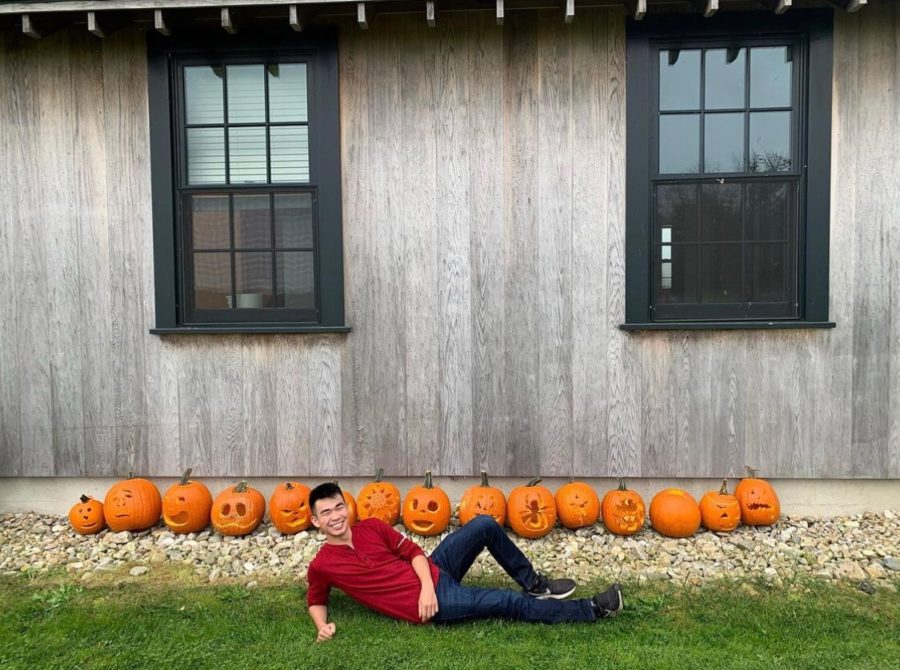 Cooper Roh 22 lies in front of pumpkins carved during the Farm Festival.